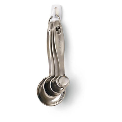 Quatro colheres medidoras de aço inoxidável penduradas em um anel de metal estão presas a um Command™ Mini-Haken, 17006 da 3M Deutschland GmbH - fixadas com segurança sem furar e fáceis de remover da parede branca sem deixar resíduos.