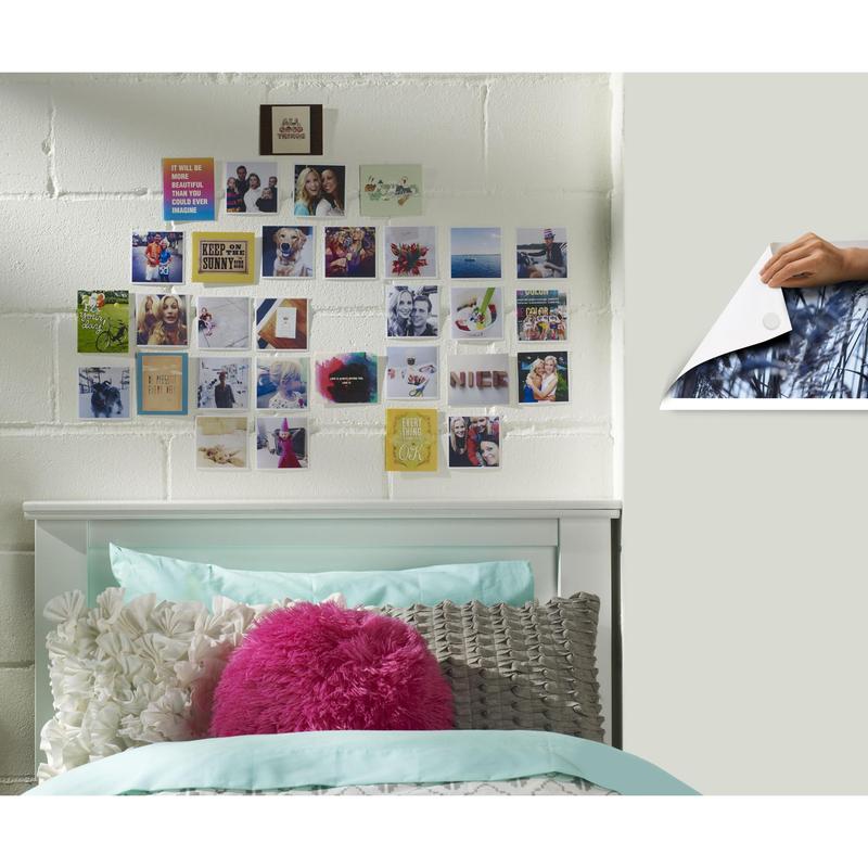 Uma cama branca com roupa de cama em tons de azul e branco está em frente a uma parede de tijolos brancos. Acima, pequenas fotos estão dispostas em uma grade com Scotch-FIX™ Almofadas Adesivas Removíveis 301008C36-P da 3M Deutschland GmbH - forte aderência, fácil remoção.