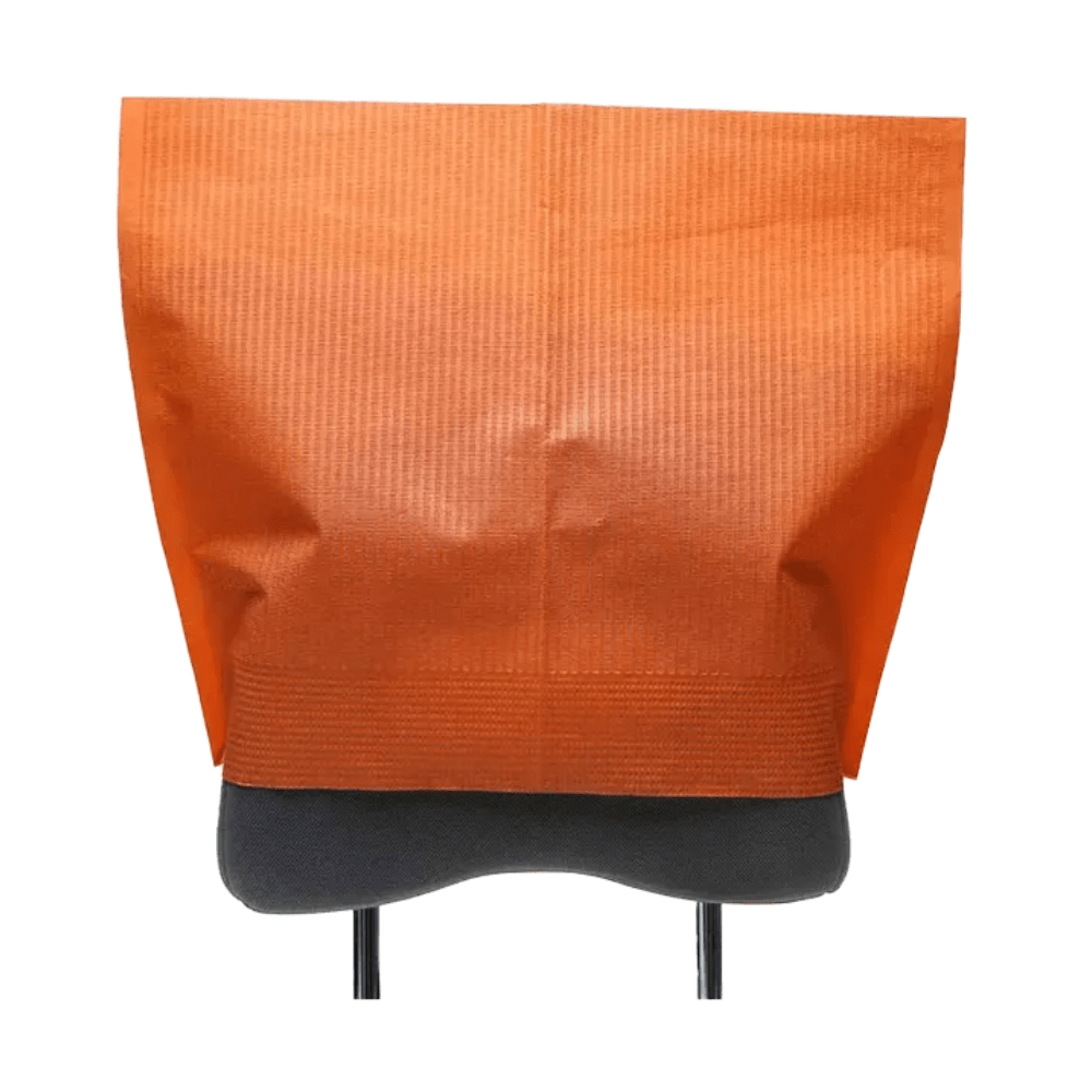 Um protetor de apoio de cabeça da AMPri Handelsgesellschaft mbH feito de tecido de papel de seda laranja está elegantemente drapeado sobre o encosto de uma cadeira cinza. Sua superfície texturizada valoriza o design, com as pernas da cadeira parcialmente visíveis abaixo. A parte superior aberta da capa oferece fácil acesso e confere a este equipamento odontológico um charme funcional.