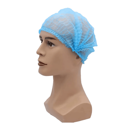 Uma cabeça de boneca usa uma touca azul AMPri MED-COMFORT Klipphaube 52 cm, da AMPri Handelsgesellschaft mbH. A rede para cabelo de polipropileno leve com bordas elásticas ajusta-se firmemente à cabeça da boneca e oferece proteção higiênica. A imagem é vista sobre um fundo branco simples.