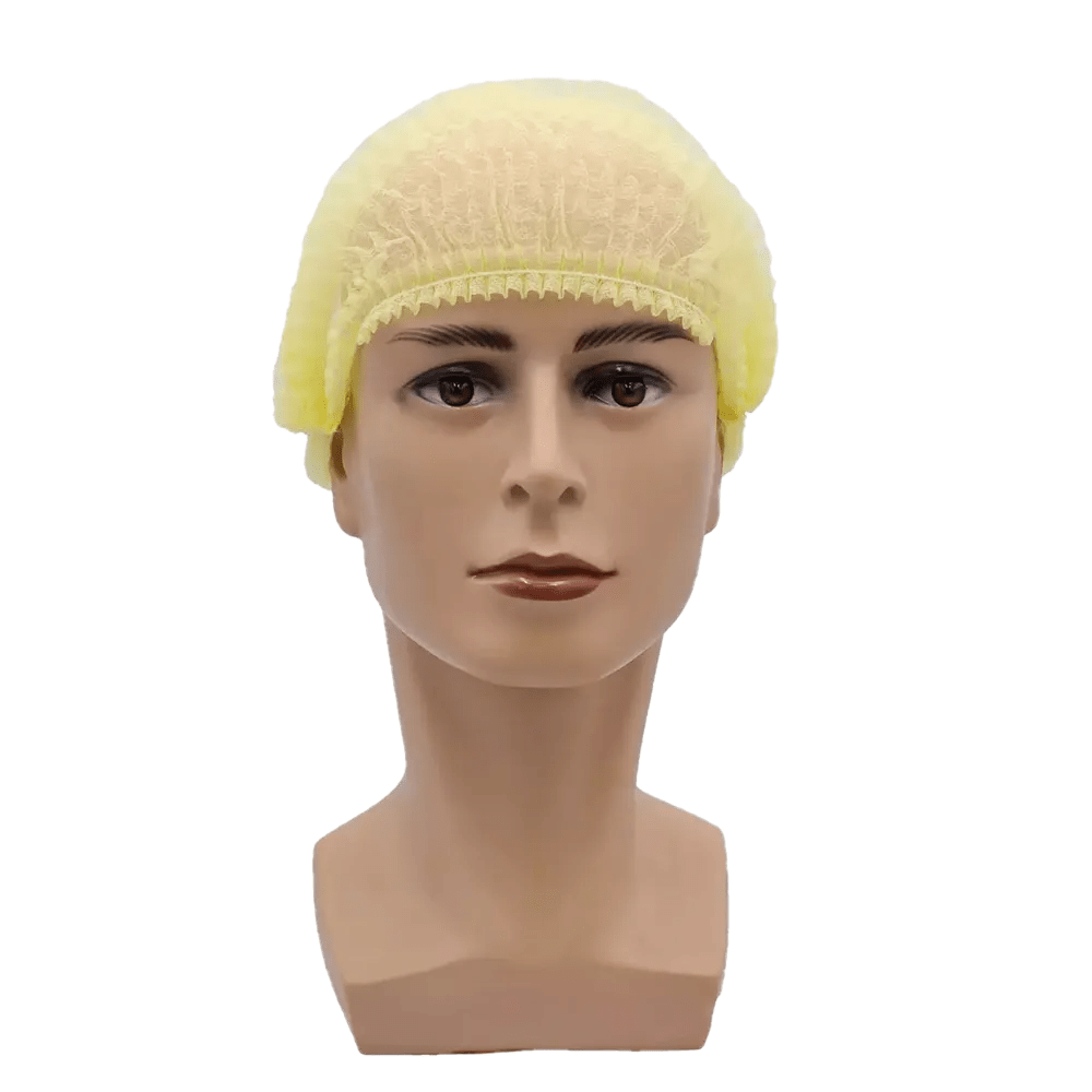 Uma cabeça de boneca apresenta uma touca amarela AMPri MED-COMFORT Klipphaube 52 cm, feita de polipropileno pela AMPri Handelsgesellschaft mbH, com uma expressão neutra contra um fundo branco simples, destacando assim a proteção higiênica.