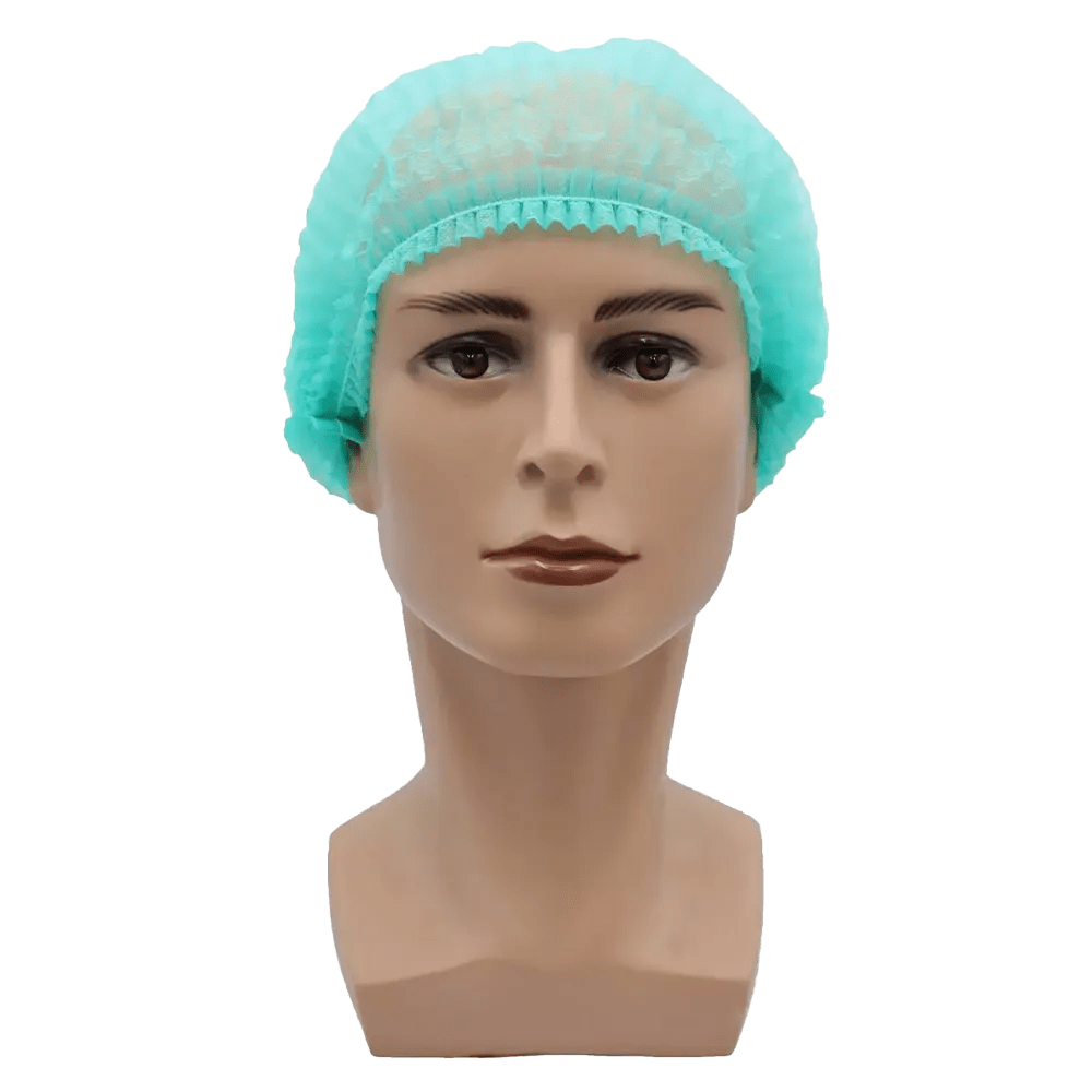 Contra um fundo branco simples, é mostrada uma cabeça de boneca bege com expressão facial neutra e cabelos curtos e escuros, coberta por uma touca AMPri MED-COMFORT Klipphaube 52 cm, em verde claro, de polipropileno da AMPri Handelsgesellschaft mbH. A touca oferece proteção higiênica.
