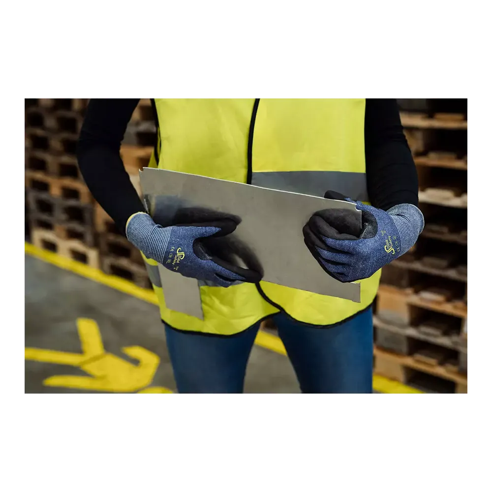 Uma pessoa com um colete de segurança amarelo neon e luvas de proteção contra cortes AMPri SolidSafety Cut S - XXL da AMPri Handelsgesellschaft mbH manuseia cuidadosamente uma grande chapa de metal no armazém. Ao fundo, paletes de madeira estão empilhados, marcações amarelas no chão guiam movimentos seguros e destacam a segurança no trabalho.