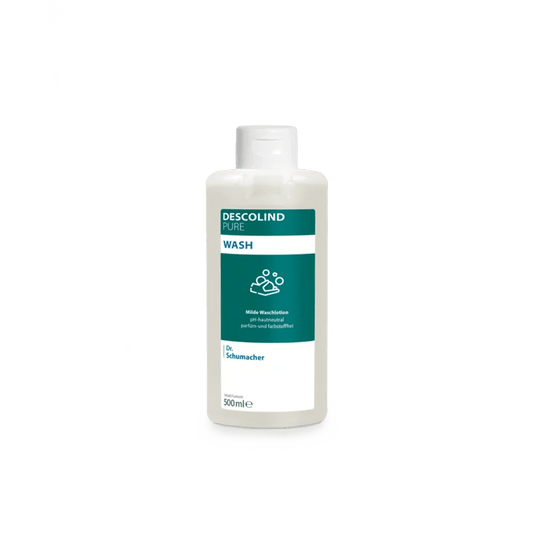 Uma garrafa de plástico branca da loção de limpeza Dr. Schumacher Descolind Pure Wash (500 ml), da Dr. Schumacher GmbH, com um rótulo verde e branco, encontra-se diante de um fundo simples de cor cinzenta clara. Esta loção de limpeza, com pH neutro para a pele e sem perfume, é ideal para peles sensíveis.