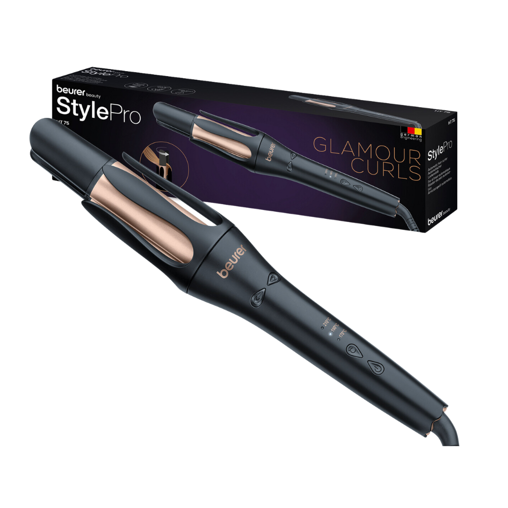 Um Beurer HT 75 Modelador Automático da Beurer GmbH em um design elegante em preto e rosa dourado é visto junto com sua caixa de embalagem com a inscrição "Glamour Curls". O modelador automático possui controles digitais no cabo e uma saída de íons 4 vezes. A caixa mostra uma imagem do modelador e a marca.