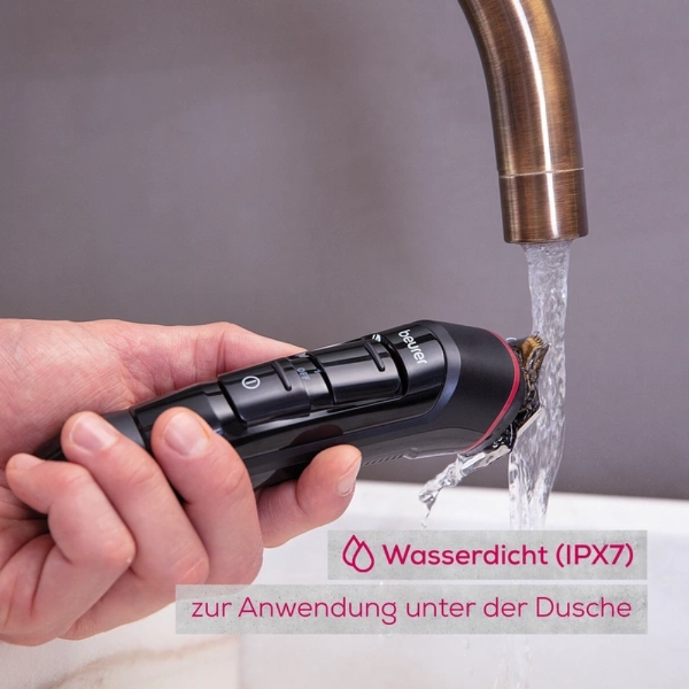 Eine Hand hält einen schwarzen elektrischen Trimmer, beschriftet mit „0“ und „1“, unter fließendes Wasser aus einem Wasserhahn. Der deutsche Text lautet „Wasserdicht (IPX7) zur Anwendung unter der Dusche“ und weist darauf hin, dass das Produkt für die Verwendung in der Dusche wasserdicht ist. Perfekt für die Körperpflege, der Beurer Multigroomer MN9X zum Trimmen und Rasieren | Packung (1 Stück) von Beurer GmbH macht die Körperpflege einfach.