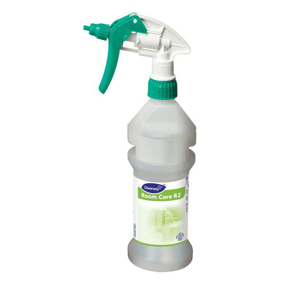 Uma garrafa de spray Room Care R2 Plus Pur-Eco transparente, vazia da Diversey Deutschland GmbH & Co. OHG com bico verde e branco está em pé sobre um fundo branco simples.