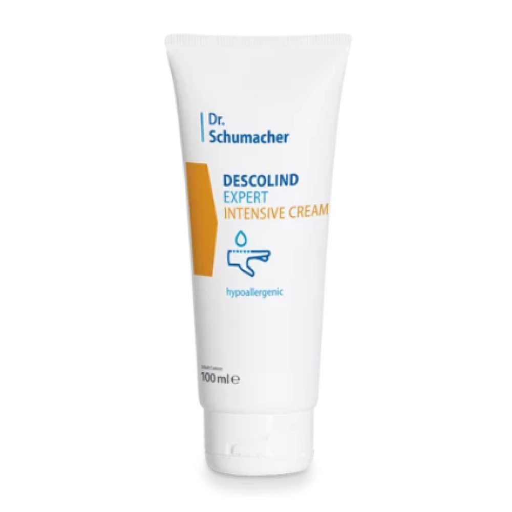 Um tubo branco com a inscrição "Dr. Schumacher Descolind Expert Creme Intensiva | Tubo (100 ml)" da Dr. Schumacher GmbH está em pé sobre um fundo simples. A embalagem apresenta um retângulo amarelo e um símbolo de gota, destacando as propriedades hipoalergénicas, tornando-a perfeita para pele sensível.