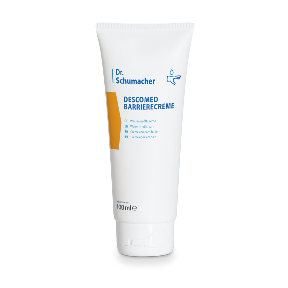 Um tubo branco de creme barreira Dr. Schumacher Descomed com uma capacidade de 100 ml, no qual o nome do produto aparece em letras azuis e um pequeno gráfico de uma gota de água. Na frente do tubo, podem-se ver várias traduções de "Barrier Cream", destacando sua identidade como um creme água-em-óleo para o cuidado das áreas da pele.