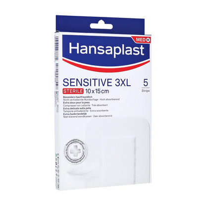 Uma embalagem de Hansaplast Sensitive XL, estéril, especialmente amigável à pele, tiras estéreis da Beiersdorf AG nas dimensões de 10 x 15 cm. A embalagem contém 5 tiras para um cuidado de feridas amigável à pele e altamente absorvente. A embalagem predominantemente branca é decorada com acentos azuis e vermelhos.