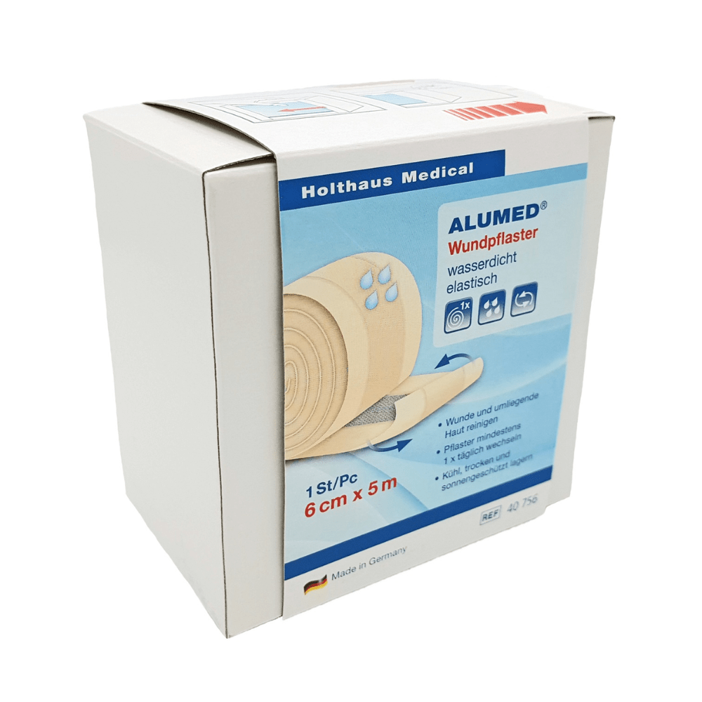 Uma caixa branca de adesivos para feridas Holthaus Alumed® 6 cm x 5 m da Holthaus Medical GmbH & Co. KG mostra uma imagem do rolo de adesivo e indica que é hipoalergénico, à prova de água e elástico. O texto na caixa do adesivo à prova de água está principalmente em alemão. O produto é fabricado na Alemanha.