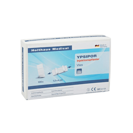 Está em exposição uma caixa de pensos injetáveis Holthaus Ypsipor da Holthaus Medical GmbH & Co. KG. A embalagem, predominantemente branca com detalhes azuis, contém 100 pensos com as dimensões de 1,5 x 4 cm. A caixa apresenta um texto em alemão e uma imagem dos pensos.