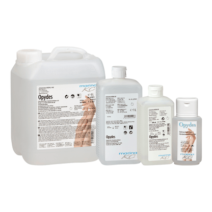 Estão representadas quatro garrafas claras da Kiehl Opydes Higiene Desinfecção das Mãos da Johannes Kiehl KG em diferentes tamanhos em fila. Elas têm letras brancas e azuis com símbolos de mãos para desinfecção higiénica das mãos e redução de germes.