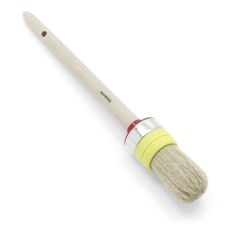 O pincel de anel profissional Nölle Profi Brush para artesãos possui cerdas naturais de alta qualidade, um cabo de madeira com orifício para armazenamento e uma virola de metal. Na área das cerdas, é decorado com uma fita amarela e acentuado com um anel vermelho acima.