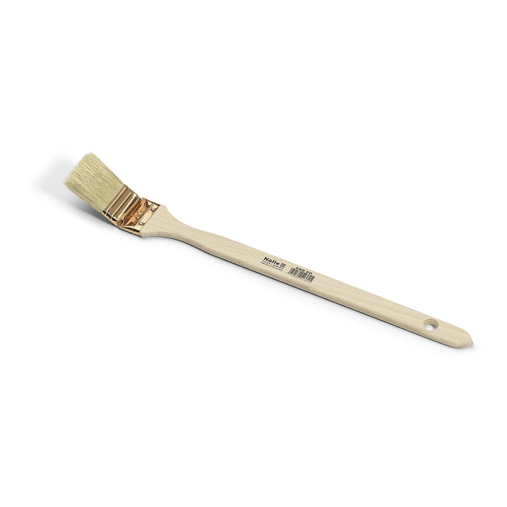 O pincel para radiadores Nölle Profi Brush possui um cabo de madeira com inscrição e orifício para pendurar, uma virola de cor cobre e cerdas chinesas claras inclinadas sobre um fundo branco.