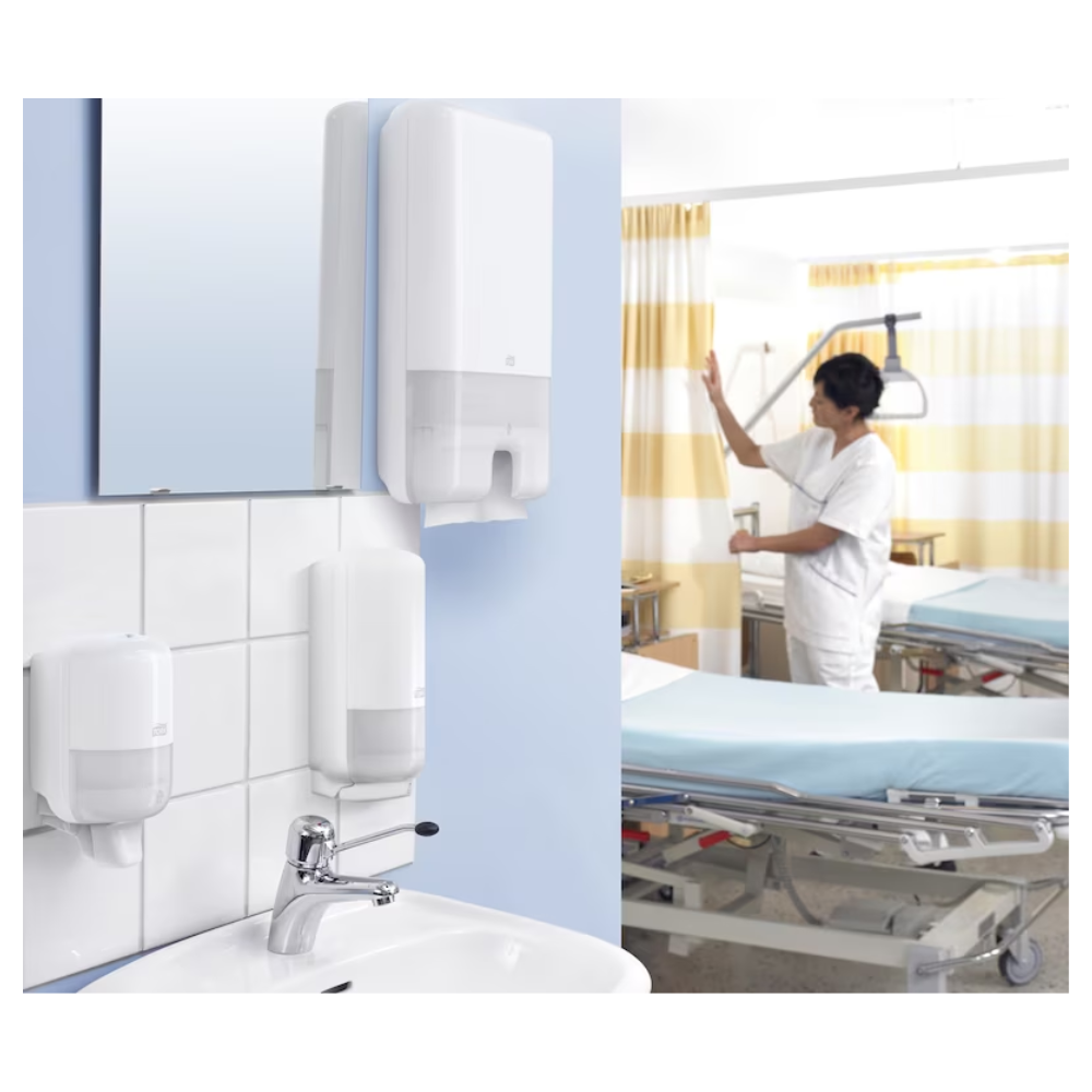 Em um quarto de hospital, um cuidador ajusta a cortina ao lado da cama de um paciente. Em primeiro plano, estão as Toalhas de Mão Multifold Tork Xpress® 471093 Universal H2 1 camada da TORK – Essity Professional Hygiene Germany GmbH ao lado de sabão universal. A cama está coberta com lençóis azuis e cercada por importantes aparelhos médicos.