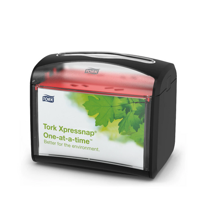 O dispensador de mesa Tork Xpressnap® 272611 para guardanapos da TORK – Essity Professional Hygiene Germany GmbH tem uma parte superior preta e uma frente transparente com um design de folha verde e a inscrição "Tork Xpressnap One-at-a-time – melhor para o ambiente". Este dispensador melhora a higiene e, ao mesmo tempo, reduz eficientemente o consumo de guardanapos.