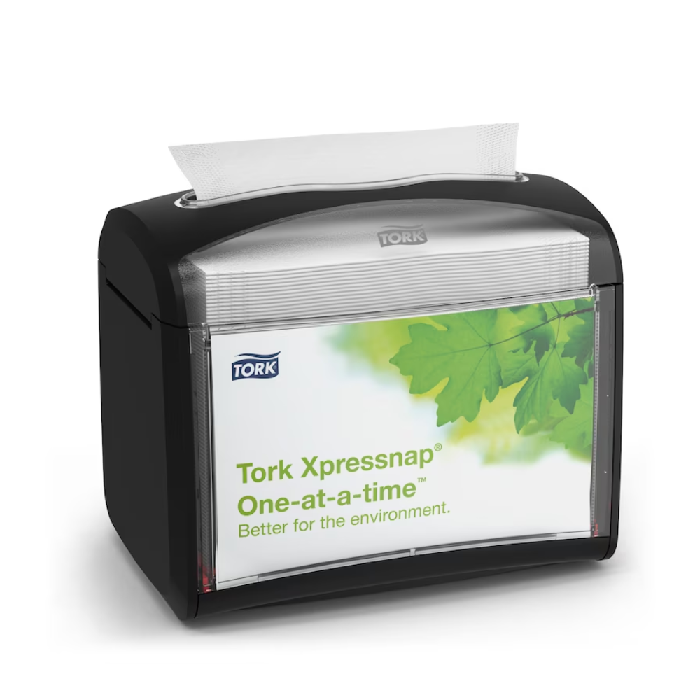 Um dispensador de mesa preto Tork Xpressnap® 272611 para guardanapos, distribuído pela TORK – Essity Professional Hygiene Germany GmbH, é apresentado com uma etiqueta com folhas verdes e a mensagem "Individualmente. Melhor para o ambiente". Um único guardanapo é parcialmente dispensado de cima para promover a higiene e um consumo eficiente de guardanapos.