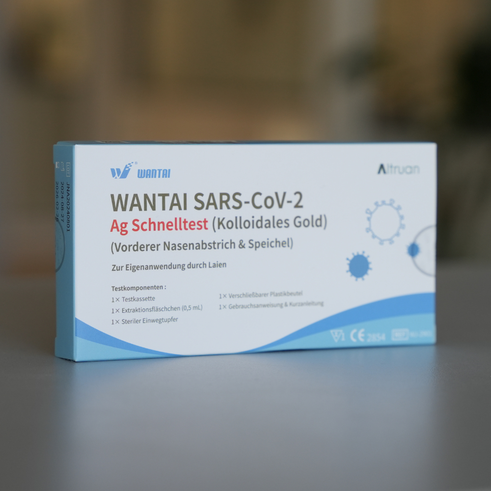 Uma caixa do teste rápido Wantai SARS-Cov-2 Lollipop com rotulagem em alemão é predominantemente embalada em branco e azul. Ela destaca a tecnologia "Ouro Coloidal" e sua adequação para amostras de nasofaringe e saliva, oferecendo assim uma opção de teste eficiente.