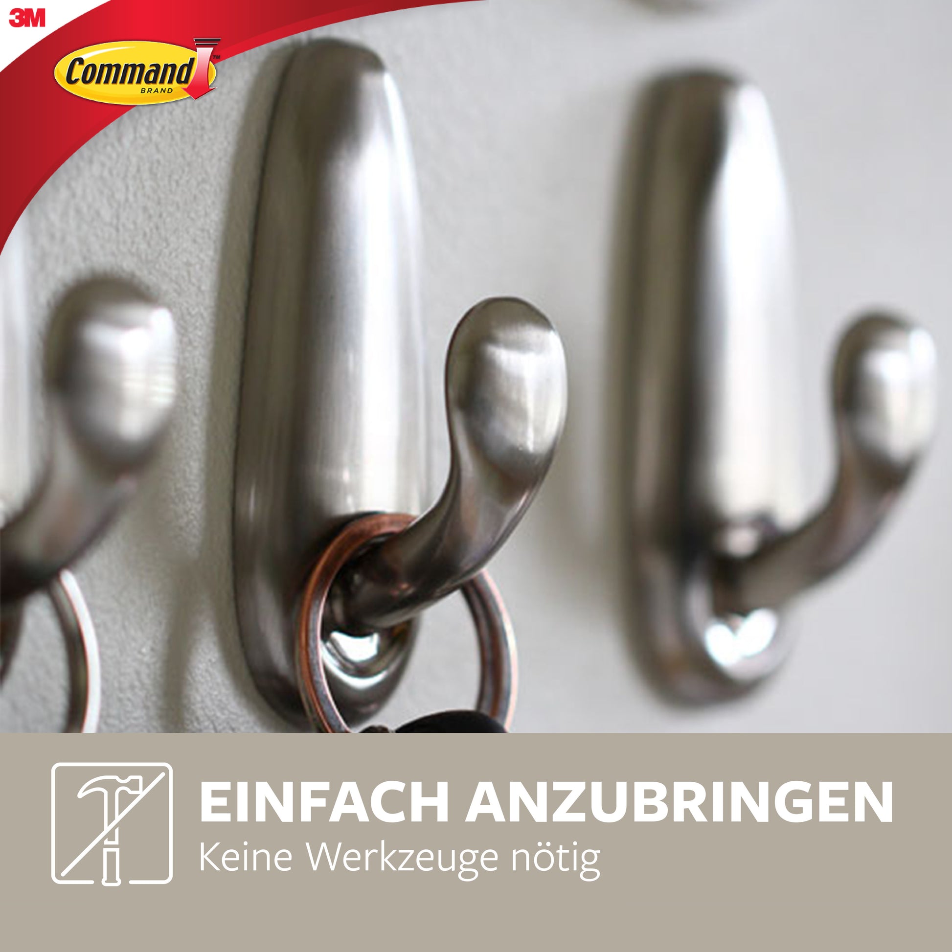 Drei Command™ Metallhaken "klassisch" von 3M Deutschland GmbH sind an einer Wand montiert, einer hält Schlüssel. Das Bild zeigt "Einfach anzubringen, keine Werkzeuge nötig" mit dem 3M-Logo in der Ecke.