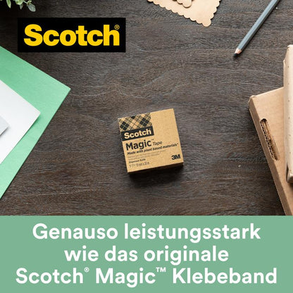 Uma caixa de fita adesiva Scotch® Magic™ (19 mm x 30 m, 1 rolo, com 66% de adesivo vegetal da 3M Deutschland GmbH) está sobre uma mesa de madeira ao lado de papel verde e branco, uma caneta e um cartão de notas. "Tão eficaz quanto a fita adesiva invisível original.