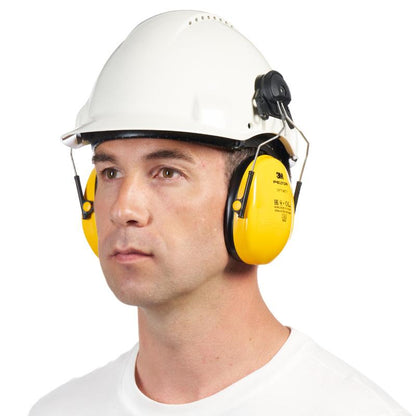 Uma pessoa com capacete branco e protetor auditivo 3M™ PELTOR™ Optime™ I H510P3E para capacete (SNR 26 dB, amarelo) da 3M Deutschland GmbH, ligeiramente voltada para a esquerda, com expressão neutra no rosto e camisa branca simples.