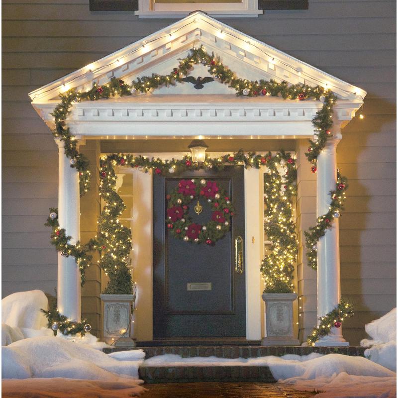 Uma entrada de Natal acolhedora brilha com luzes que foram penduradas com os clipes de luzes externas Command™, 17017CLR-AWPU (8 clipes + 10 tiras) da 3M Deutschland GmbH, neve nos degraus e guirlandas emoldurando a porta escura, para uma fixação charmosa de iluminação exterior.