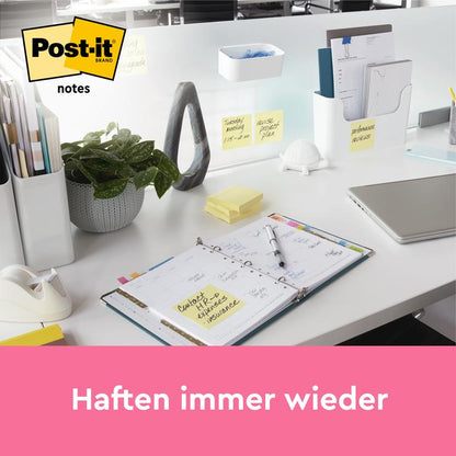 Uma mesa de escritório organizada mostra Post-it® Notes, Amarelo, 38 mm × 51 mm (100 folhas/bloco, 12 blocos/embalagem, 100% PEFC) da 3M Deutschland GmbH. As notas são visíveis na mesa e na divisória. O texto abaixo diz: "Adere sempre novamente.