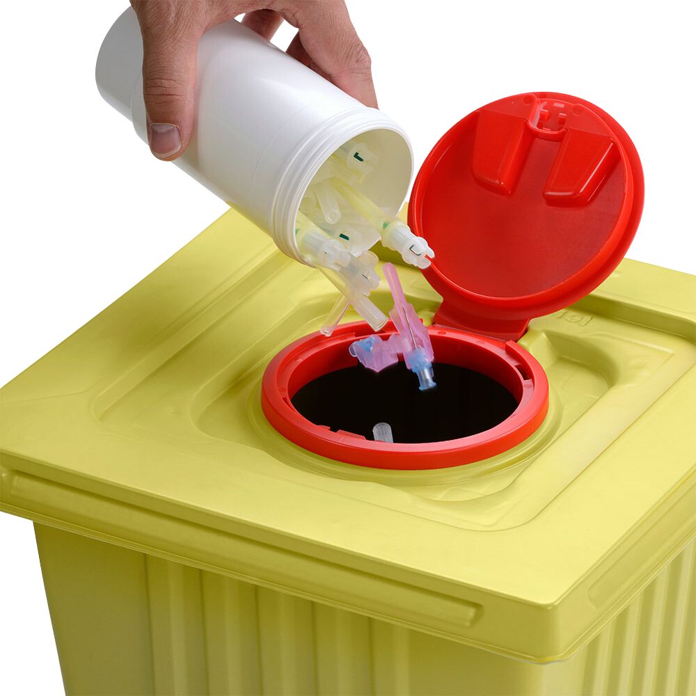 Uma mão descarta pontas de seringas usadas de um recipiente de eliminação branco Helmut Schwarz GmbH melijekt 12 L em um recipiente de resíduos médicos amarelo com tampa vermelha, garantindo assim o descarte adequado.