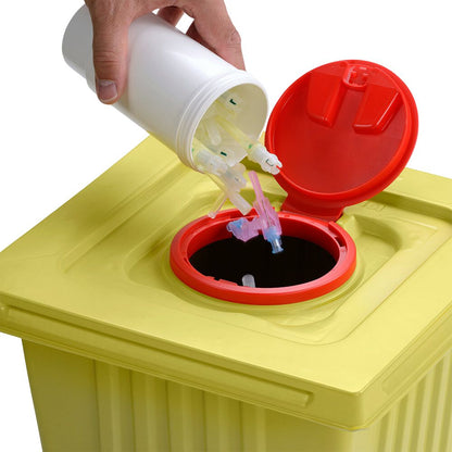 Uma mão descarta pontas de seringas usadas de um recipiente de eliminação branco Helmut Schwarz GmbH melijekt 12 L em um recipiente de resíduos médicos amarelo com tampa vermelha, garantindo assim o descarte adequado.