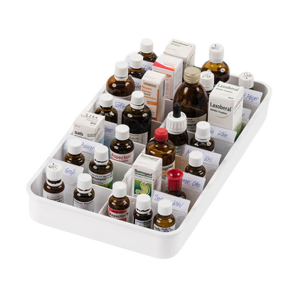 A pastilha melipul Anbruchtropfen com 14 compartimentos da Helmut Schwarz GmbH organiza elegantemente uma seleção de frascos e caixas homeopáticos e apresenta uma seleção clara de medicamentos líquidos. Os compartimentos contêm recipientes de diferentes tamanhos e cores, principalmente frascos de vidro castanho e caixas brancas, alguns com rótulos visíveis.